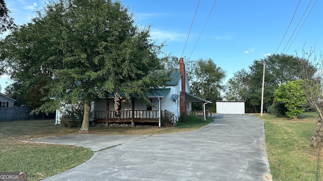 view of front of home with an outdoor structure, a front lawn, and covered porch