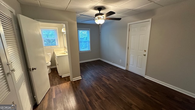 unfurnished bedroom with a drop ceiling, dark hardwood / wood-style floors, ceiling fan, and sink