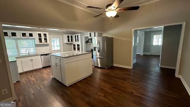 kitchen with a wealth of natural light, a kitchen island, appliances with stainless steel finishes, and white cabinetry