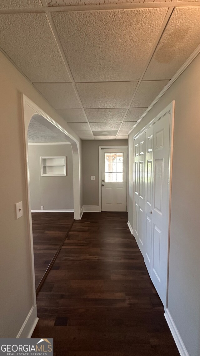 corridor featuring a drop ceiling and dark wood-type flooring