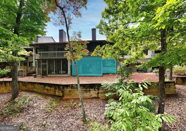 back of house featuring a sunroom and a chimney