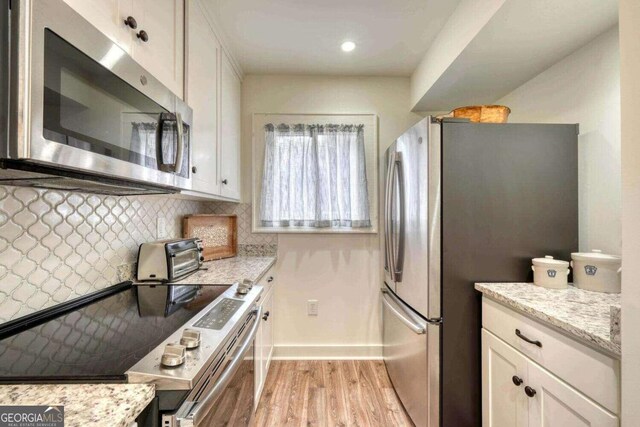 kitchen featuring light wood finished floors, white cabinetry, decorative backsplash, and appliances with stainless steel finishes