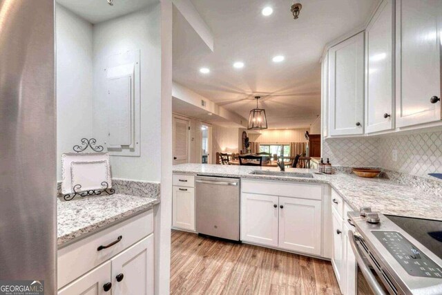 kitchen with light wood-style flooring, backsplash, white cabinets, appliances with stainless steel finishes, and a sink