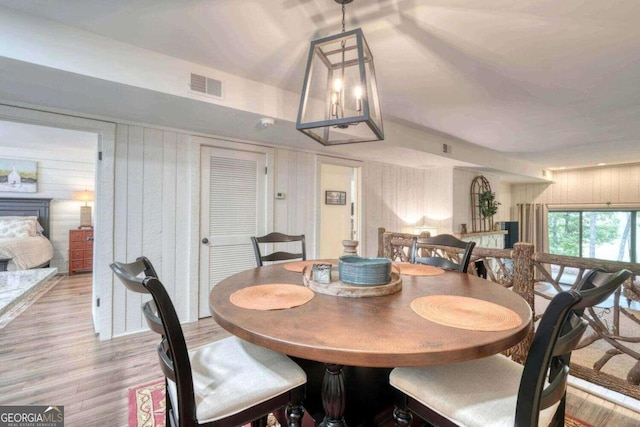 dining space featuring light hardwood / wood-style flooring, wood walls, and a fireplace