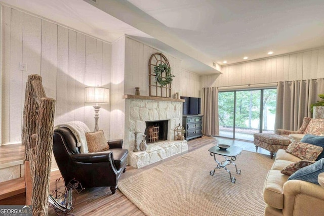 living area with wood finished floors, wood walls, a fireplace, and recessed lighting