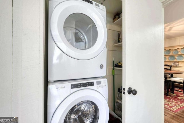 clothes washing area with stacked washer and clothes dryer and wood-type flooring