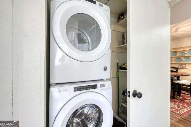 washroom with stacked washing maching and dryer and wood finished floors