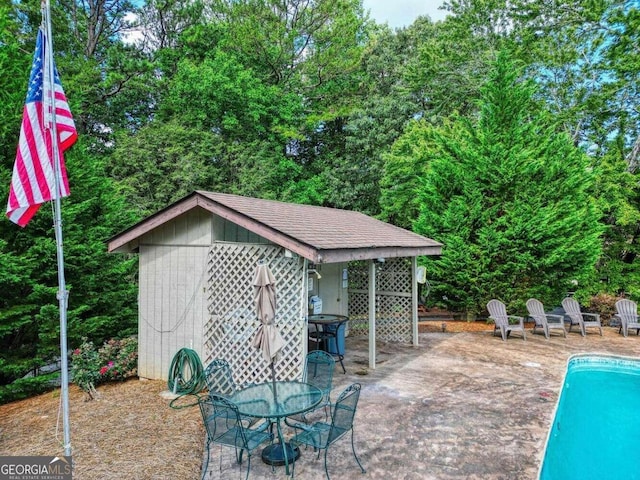 outdoor pool with a patio area and an outbuilding