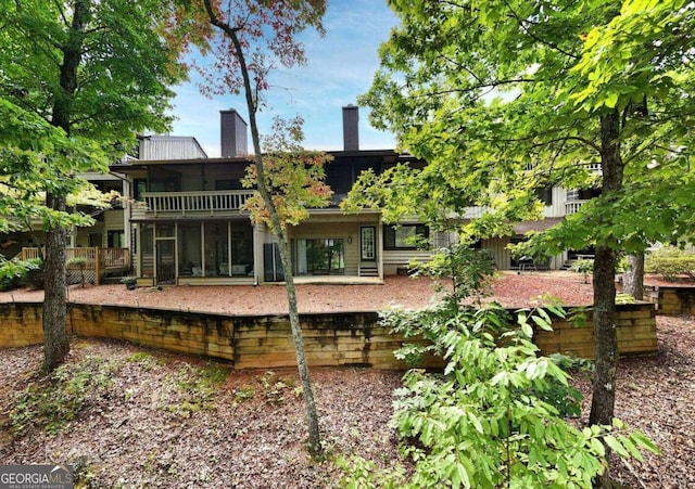 rear view of property with a sunroom and a chimney