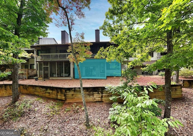 rear view of property featuring a sunroom and a chimney