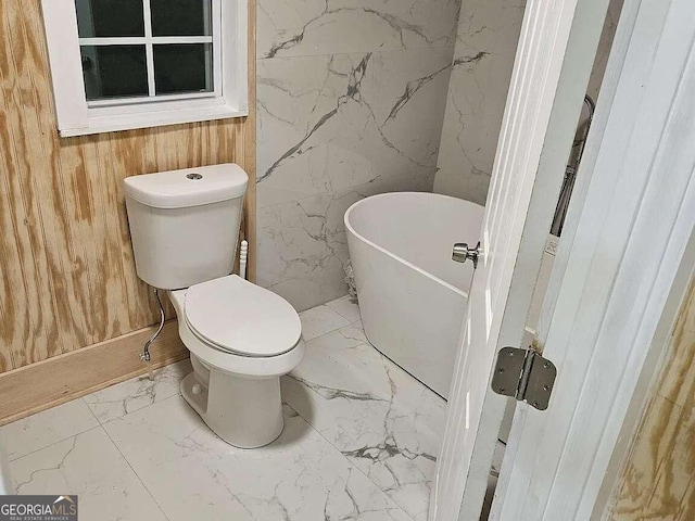 bathroom with wooden walls, a bathtub, and toilet