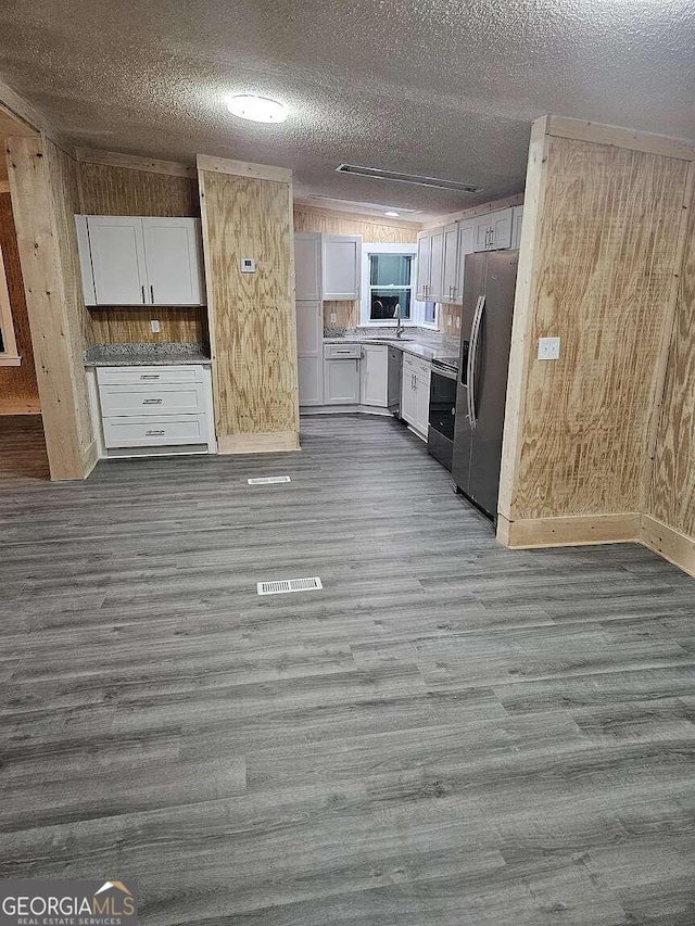 kitchen with wood-type flooring, a textured ceiling, appliances with stainless steel finishes, and white cabinetry