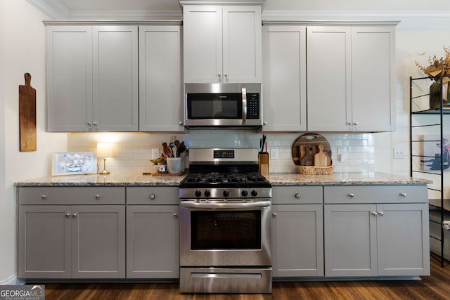 kitchen with light stone counters, appliances with stainless steel finishes, backsplash, and dark hardwood / wood-style flooring