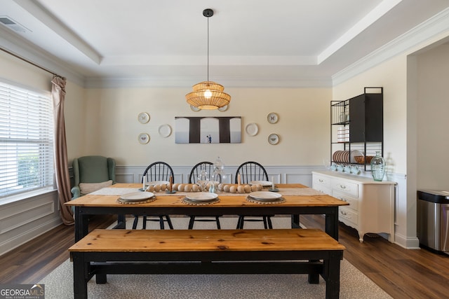 dining space with ornamental molding, a raised ceiling, and dark wood-type flooring