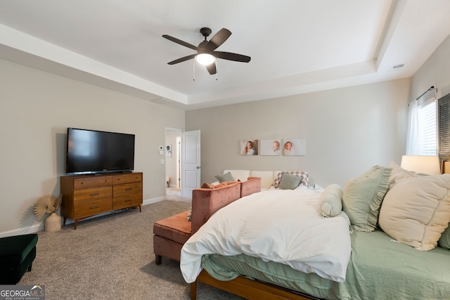 bedroom with a tray ceiling, ceiling fan, and carpet floors