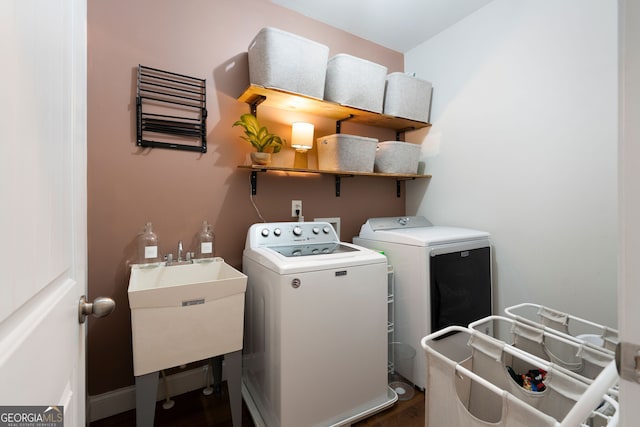 laundry area featuring wood-type flooring, washer and clothes dryer, and sink