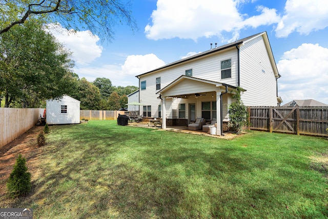 rear view of property with ceiling fan, a patio, a storage unit, outdoor lounge area, and a yard