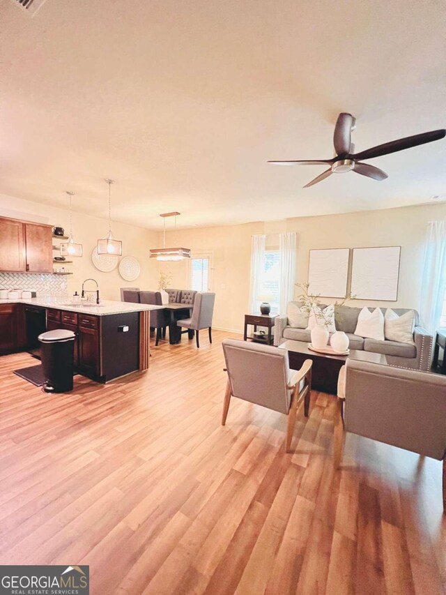 living room featuring light wood-type flooring, ceiling fan, and sink