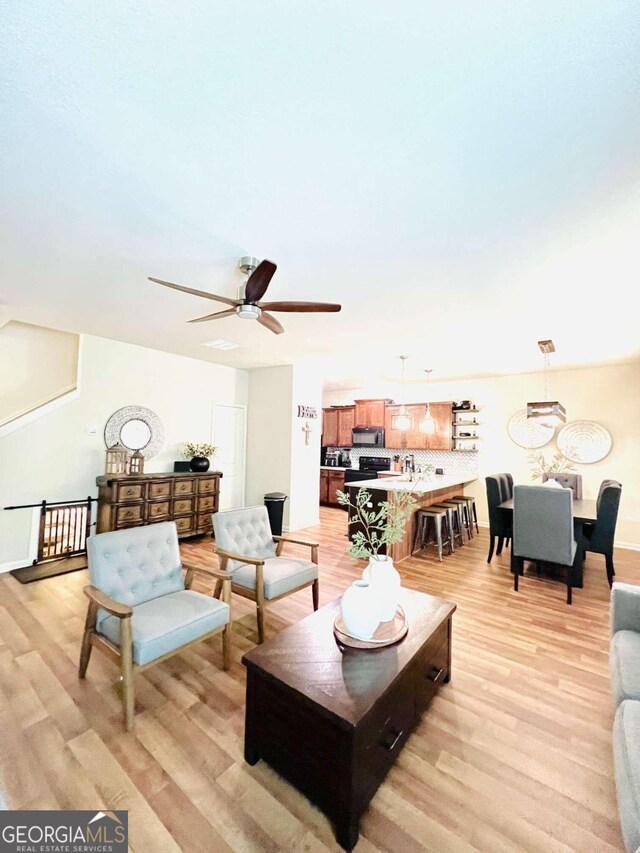 living room featuring ceiling fan and light hardwood / wood-style flooring