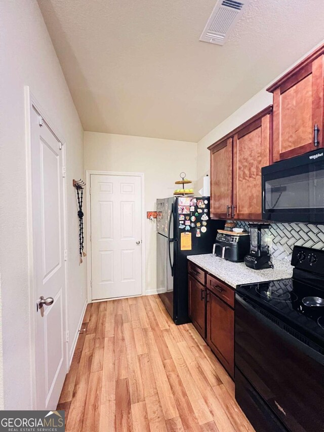 kitchen featuring light hardwood / wood-style floors, tasteful backsplash, and black appliances