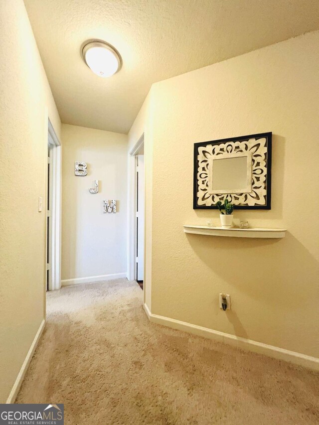 corridor with a textured ceiling and carpet flooring