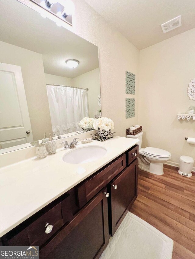 bathroom featuring vanity, toilet, and hardwood / wood-style flooring