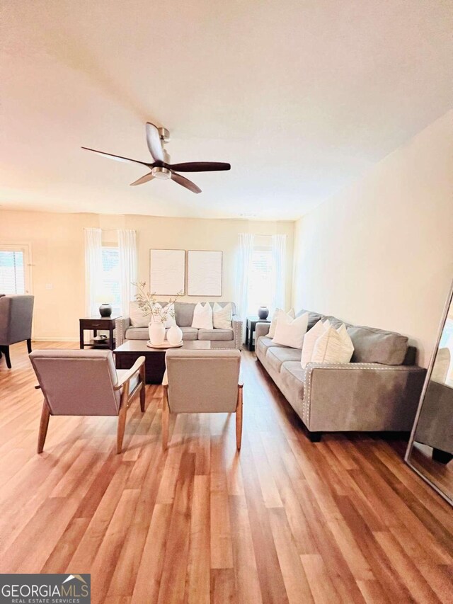 living room featuring wood-type flooring, ceiling fan, and a wealth of natural light