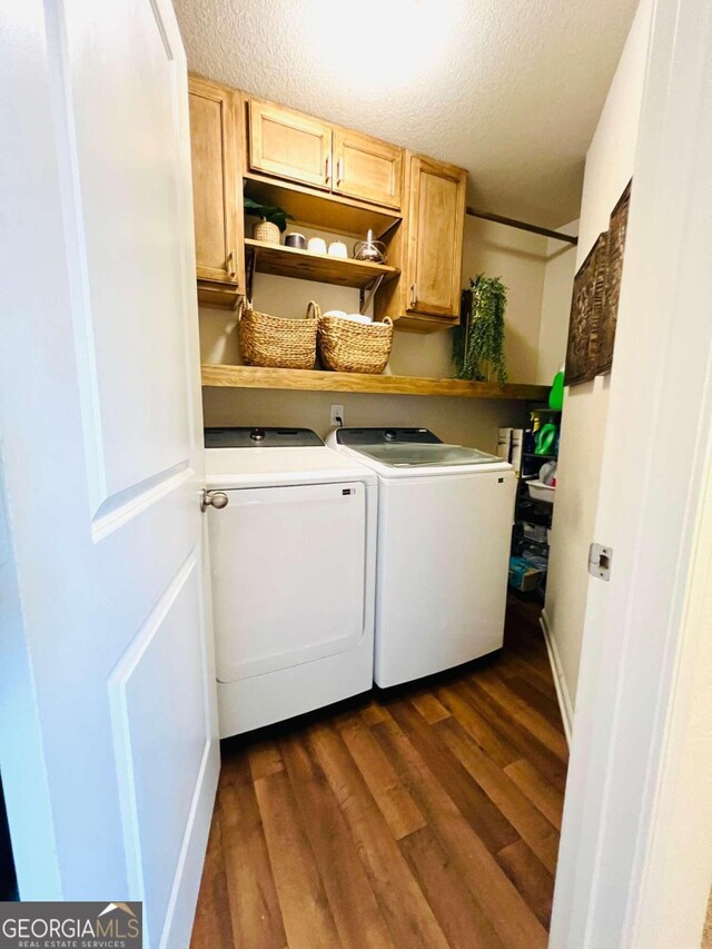 laundry room with cabinets, a textured ceiling, dark hardwood / wood-style floors, and washer and dryer