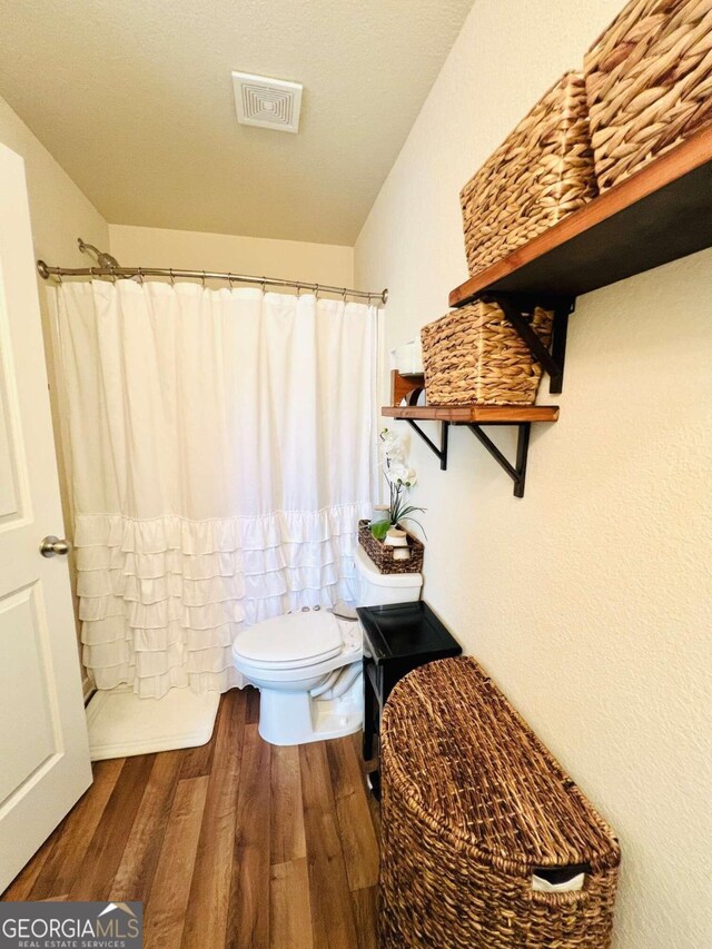 bathroom featuring hardwood / wood-style floors, toilet, and curtained shower