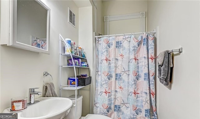 bathroom featuring toilet, walk in shower, and sink