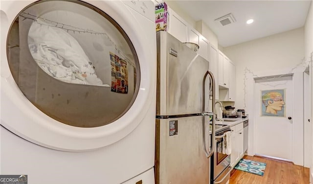 kitchen featuring light wood-type flooring, washer / clothes dryer, sink, white cabinets, and stainless steel appliances