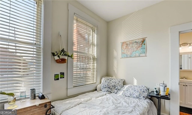 bedroom with hardwood / wood-style flooring, ensuite bath, sink, and multiple windows