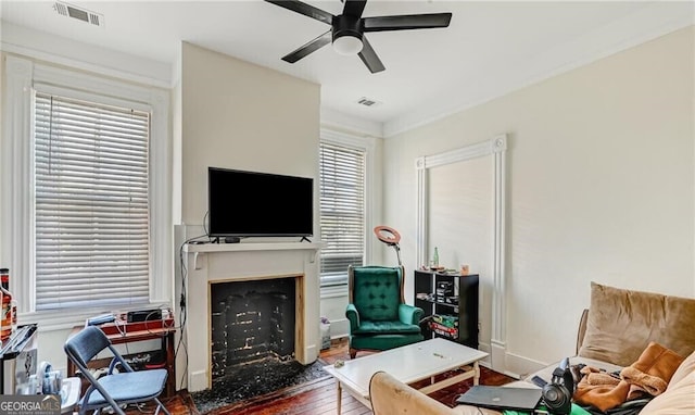 living room featuring a wealth of natural light, ceiling fan, a fireplace, and dark hardwood / wood-style flooring