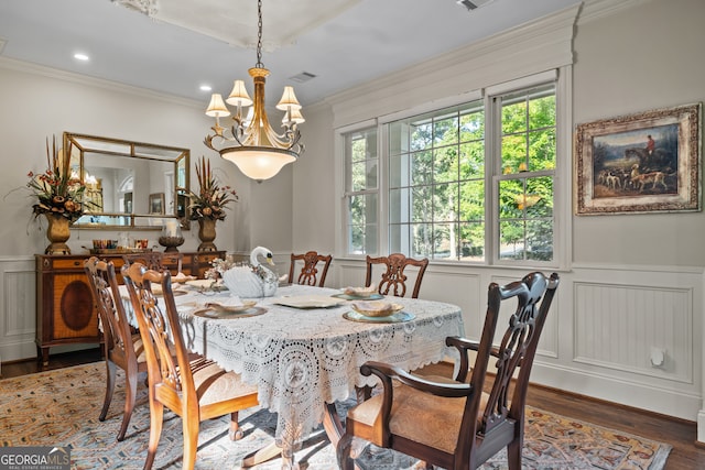 dining area with a notable chandelier, ornamental molding, and dark hardwood / wood-style flooring