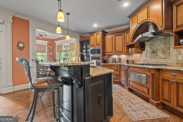 kitchen featuring light stone countertops, a kitchen breakfast bar, stainless steel appliances, dark wood-type flooring, and a kitchen island with sink