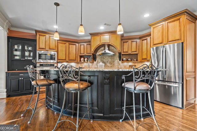 kitchen featuring light stone countertops, an island with sink, hardwood / wood-style floors, stainless steel appliances, and a breakfast bar area