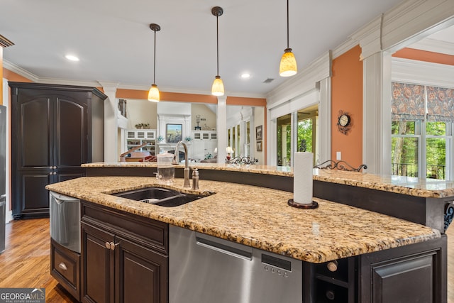 kitchen with a kitchen island with sink, ornamental molding, sink, stainless steel dishwasher, and light hardwood / wood-style floors