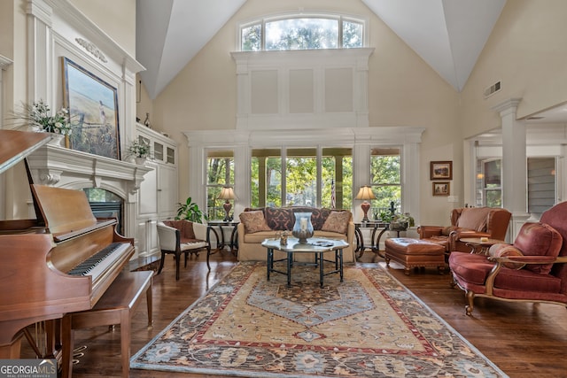 living room featuring a high end fireplace, dark hardwood / wood-style floors, high vaulted ceiling, and decorative columns