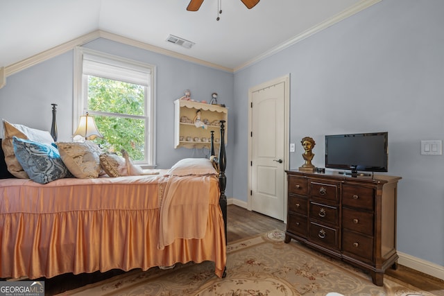 bedroom with lofted ceiling, hardwood / wood-style floors, ornamental molding, and ceiling fan