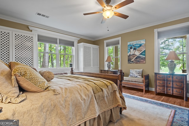 bedroom featuring hardwood / wood-style floors, crown molding, and ceiling fan