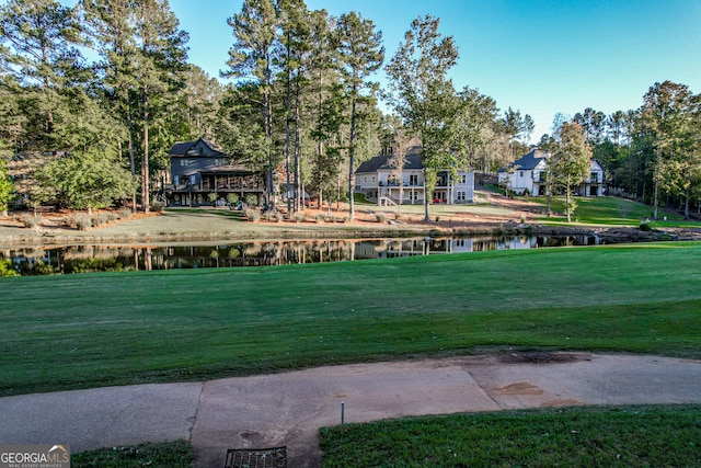 surrounding community with a water view and a lawn