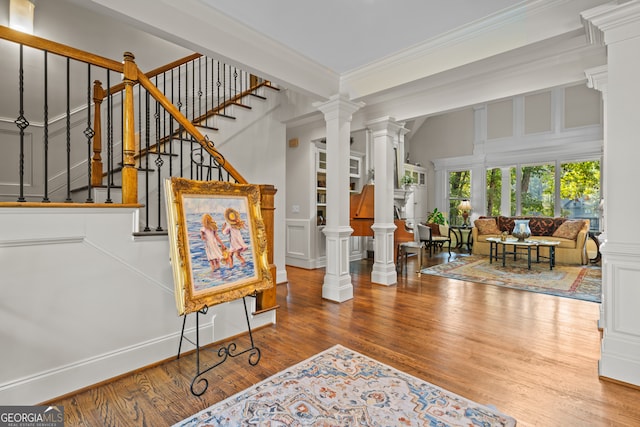 interior space featuring hardwood / wood-style floors, crown molding, and decorative columns