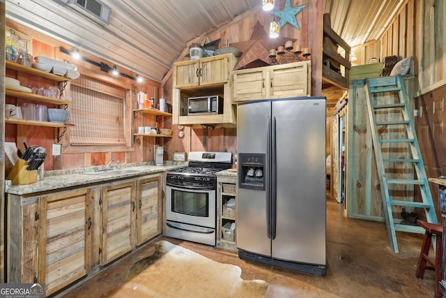 kitchen with light stone countertops, sink, vaulted ceiling, wooden walls, and appliances with stainless steel finishes