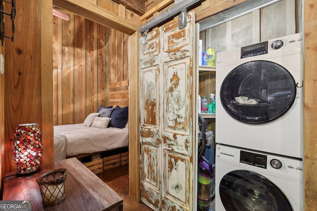 laundry area featuring stacked washer and dryer and wood walls