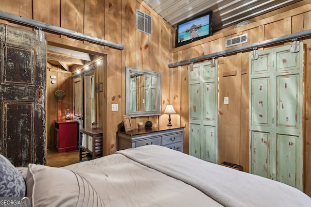 carpeted bedroom with a barn door, wooden walls, and vaulted ceiling