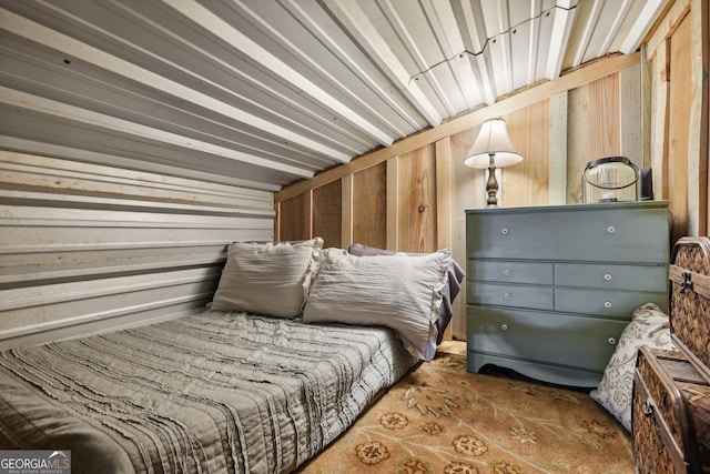 carpeted bedroom featuring wooden walls