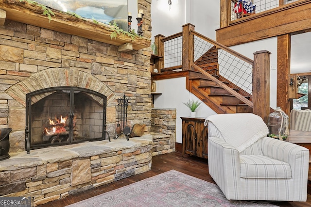 living room with a stone fireplace and dark hardwood / wood-style flooring