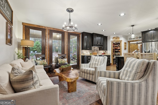 living room with wood-type flooring, a barn door, an inviting chandelier, and a wealth of natural light