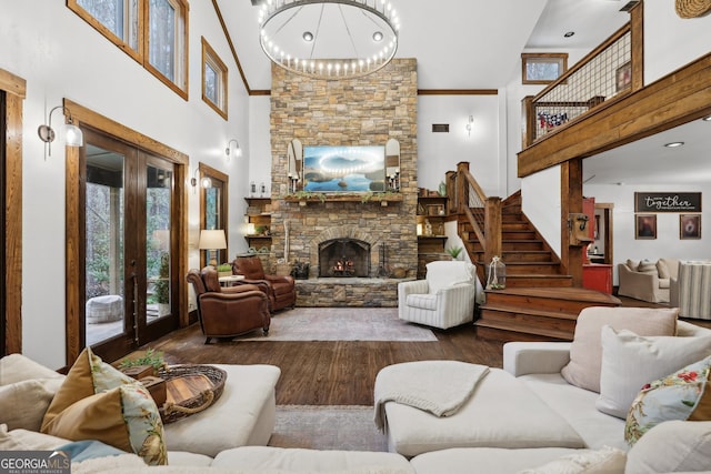 living room with a fireplace, hardwood / wood-style floors, a towering ceiling, and french doors