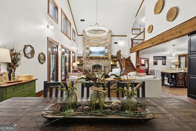 dining room with a chandelier, a towering ceiling, a fireplace, and dark wood-type flooring